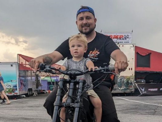 Jonathan Hurst is riding a motorcycle with his little boy Cameron on his lap