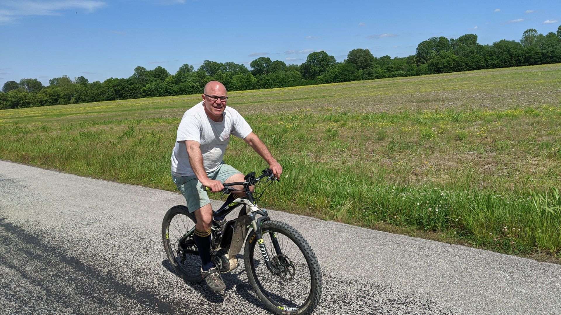 A man is riding a bike on a gravel road.