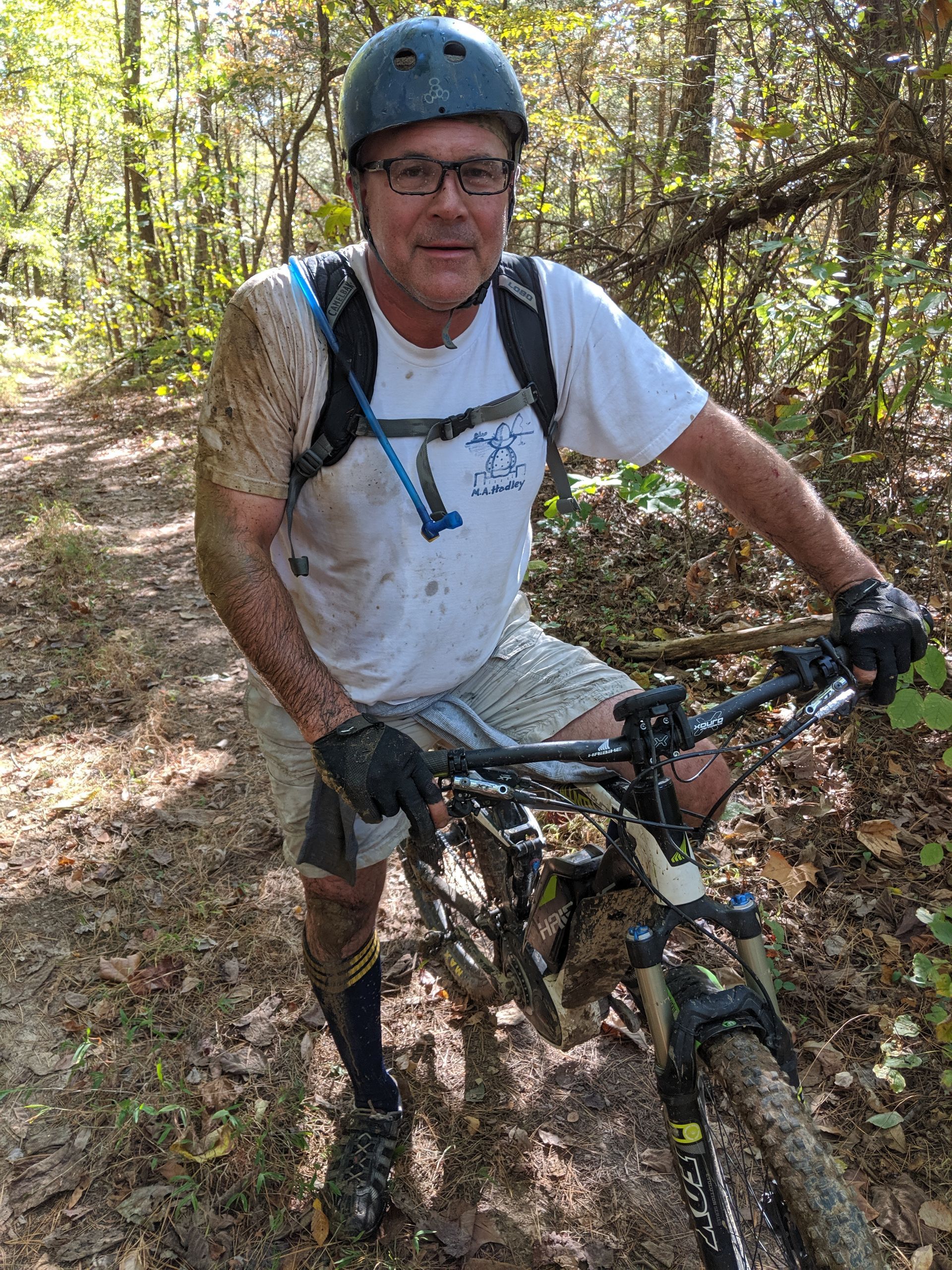 A man is riding a mountain bike on a muddy trail in the woods.