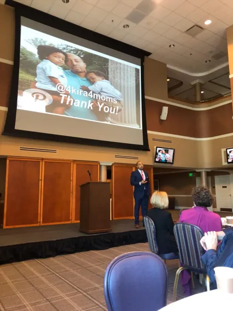 A doctor, businessman, and nurse converse in a well-lit office, surrounded by other staff.