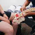 A practitioner examines a person's back, palpating the spine and lumbar region while they sit in a clinical setting.