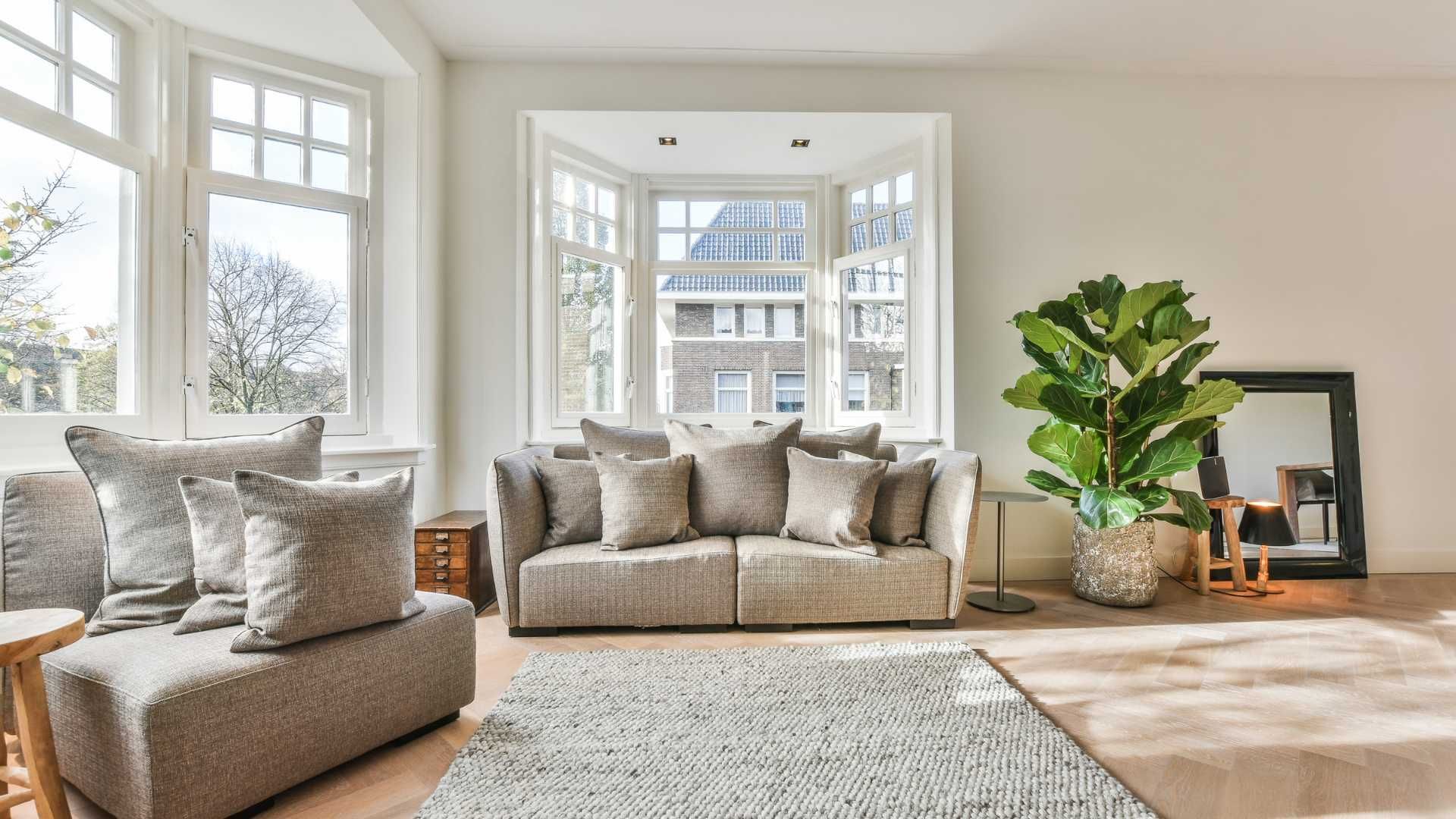 A living room with a couch , chair , rug and a large window.