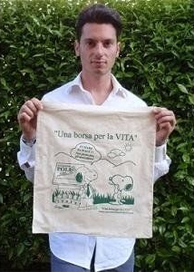 Uomo che tiene in mano una borsa di tela con illustrata una scena all'aperto.