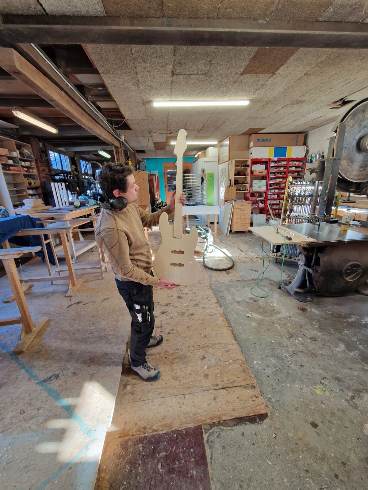 Un jeune garçon tient une croix en bois dans un atelier.