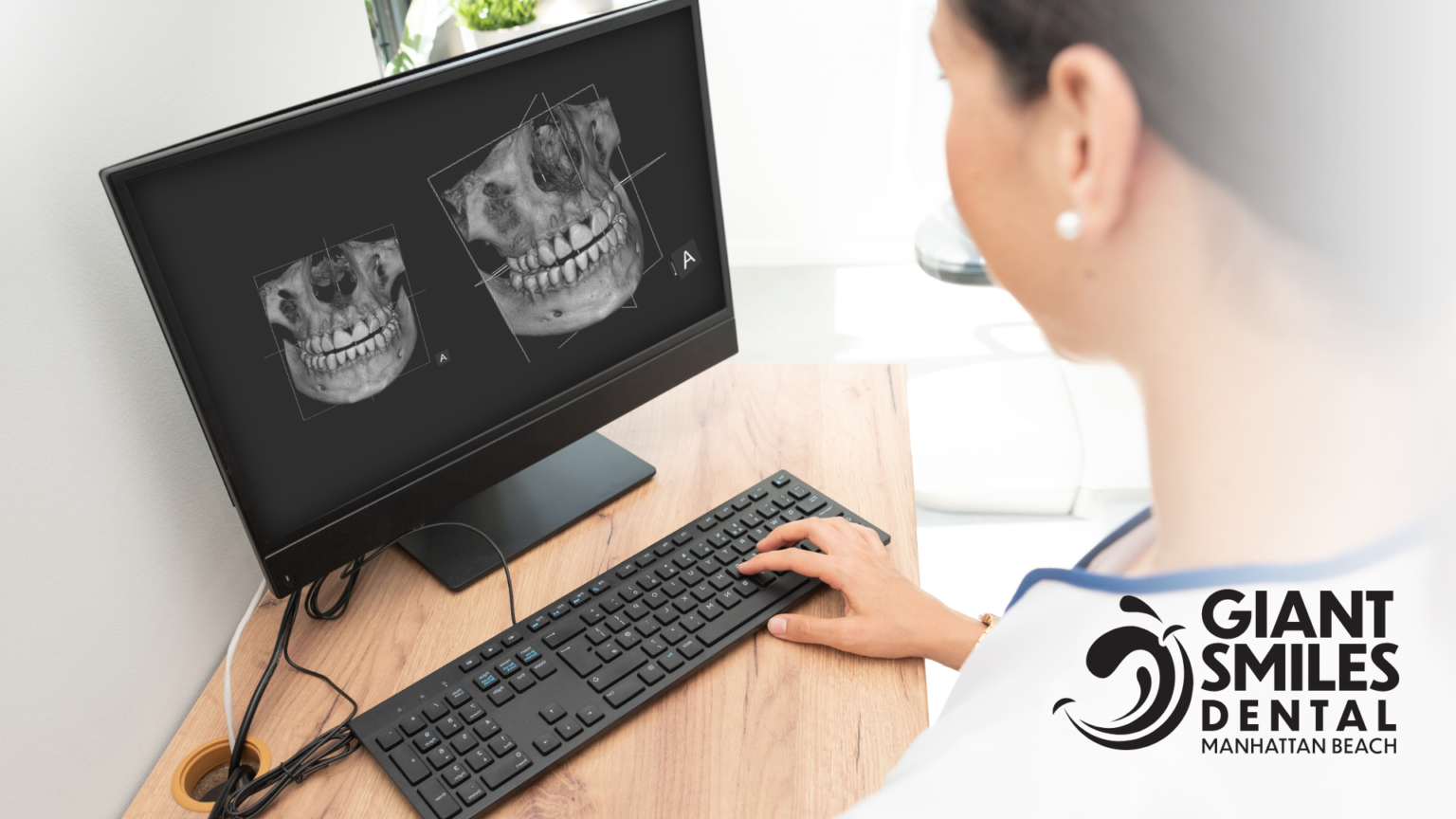 A woman is sitting at a desk looking at an x-ray on a computer screen.