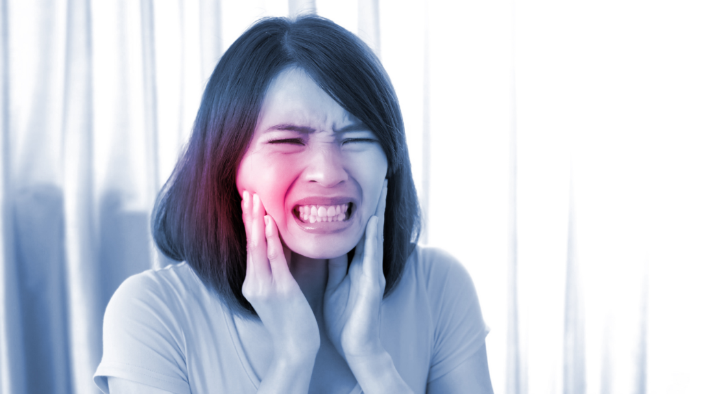 A woman is holding her face in pain because of a toothache.