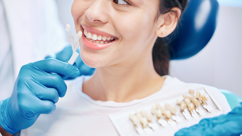 A woman is sitting in a dental chair while a dentist examines her teeth.