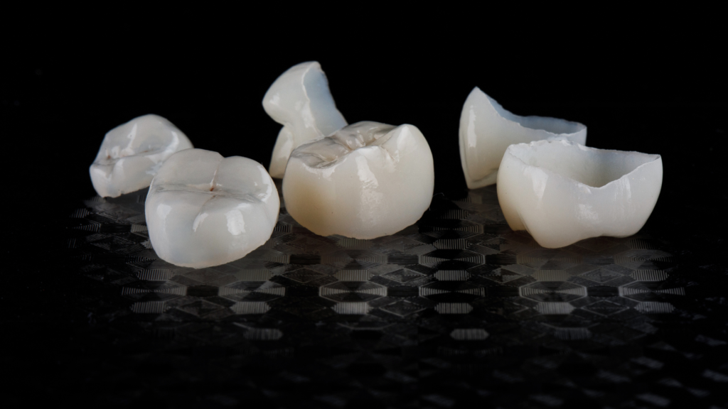 A group of dental crowns are sitting on a black surface.