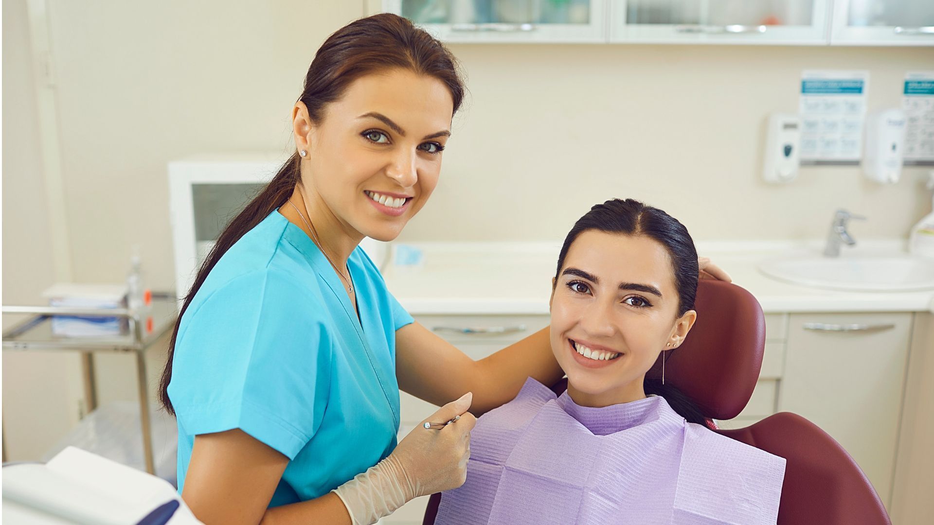 Dental assistant smiling beside a patient in a dental chair during a checkup