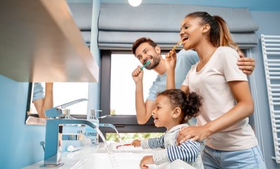 A family is brushing their teeth together in a bathroom.