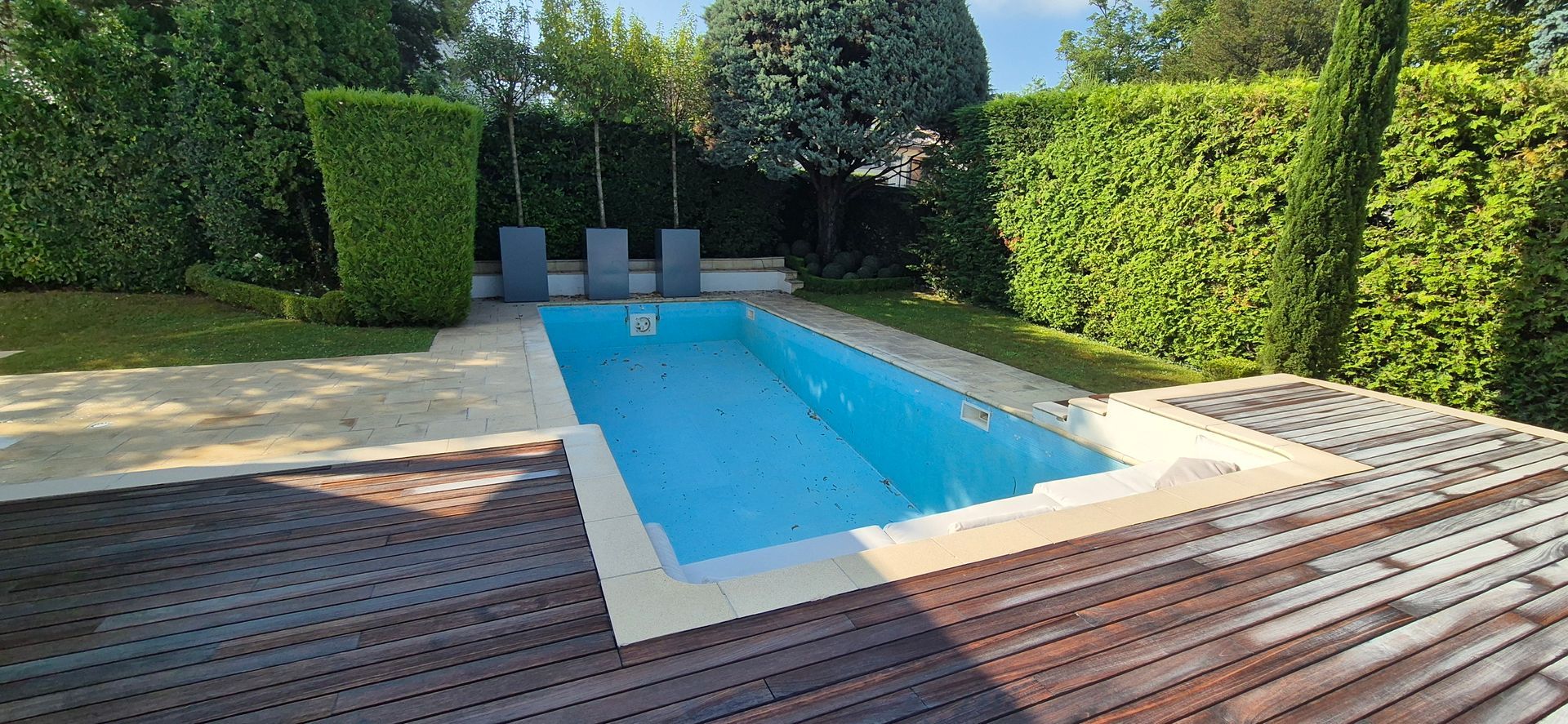 Une grande piscine entourée d'arbres et d'une terrasse en bois.