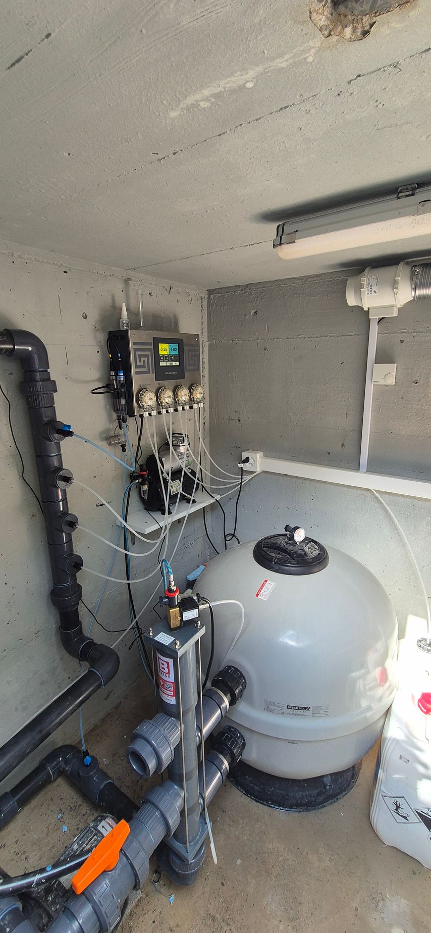 Une pompe de piscine est installée dans une pièce à côté d'un mur.