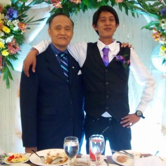 Two men in formal wear at a table with food, one with his arm around the other.