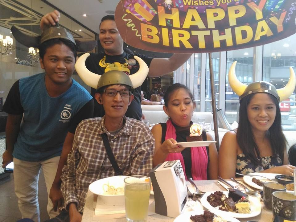 Group of people at a restaurant celebrating a birthday, wearing Viking hats and holding a birthday sign.