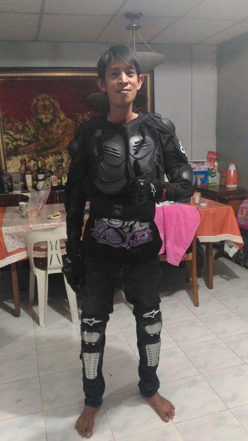 Person wearing motorcycle protective gear, standing indoors, smiling.