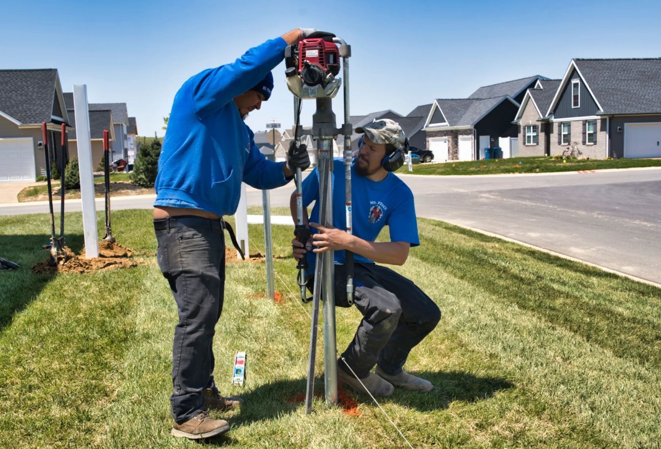 Two men are working on a fence in a residential area.