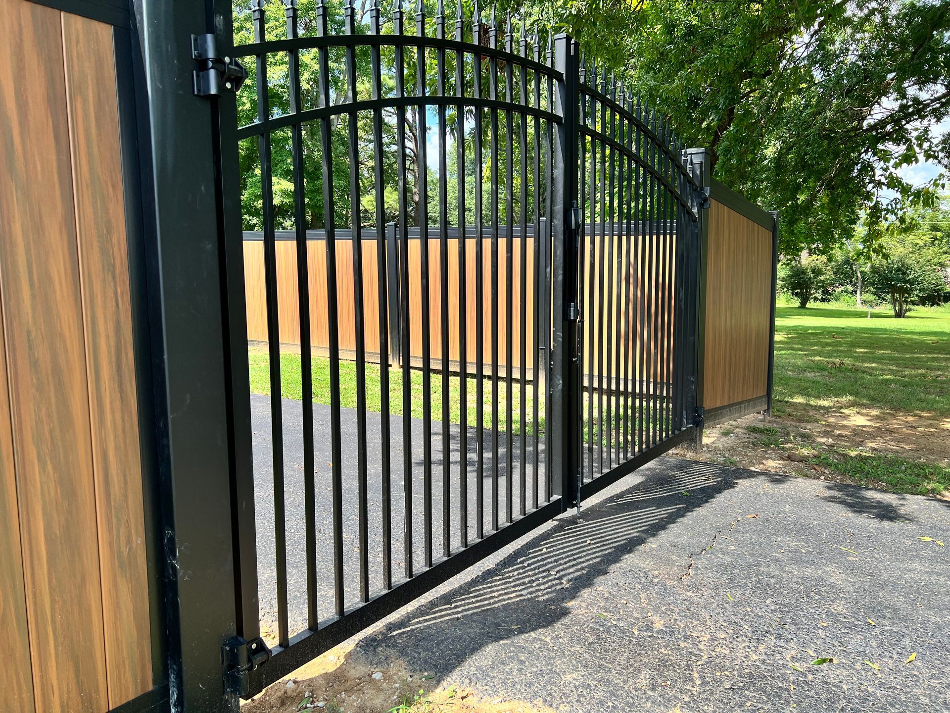 A wrought iron gate with a wooden fence behind it.