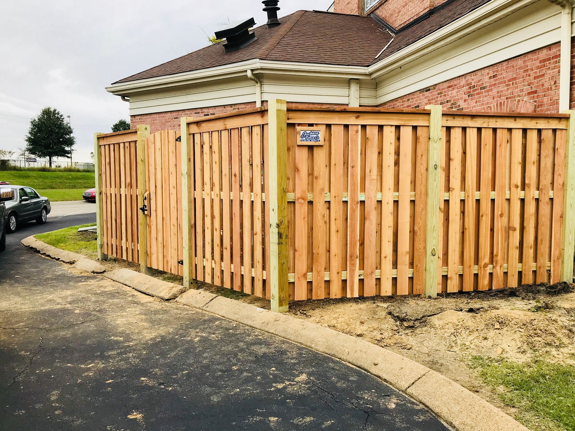 A wooden fence is in front of a house.