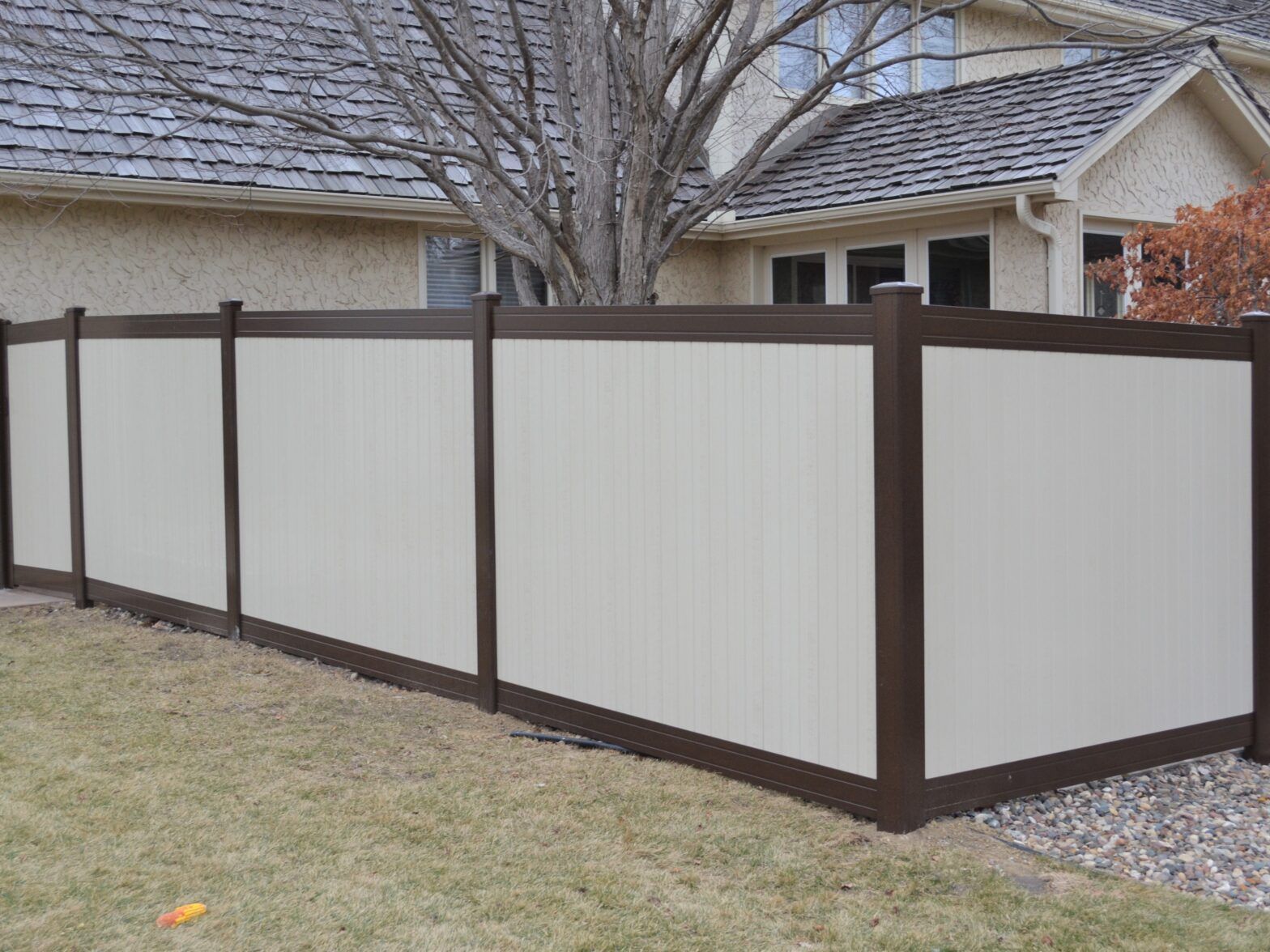 A white and brown fence is in front of a house.