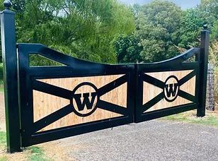 A black and wooden gate with the letter w on it.