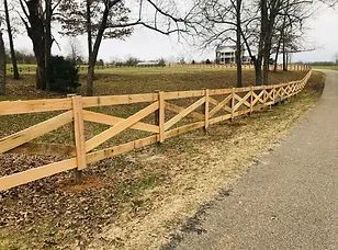 A wooden fence is along the side of a road.