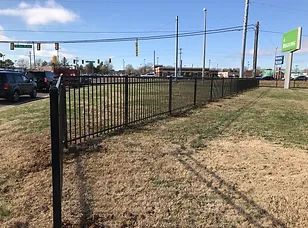 A black metal fence surrounds a grassy field.