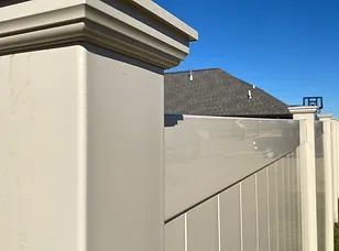 A close up of a white fence with a house in the background.