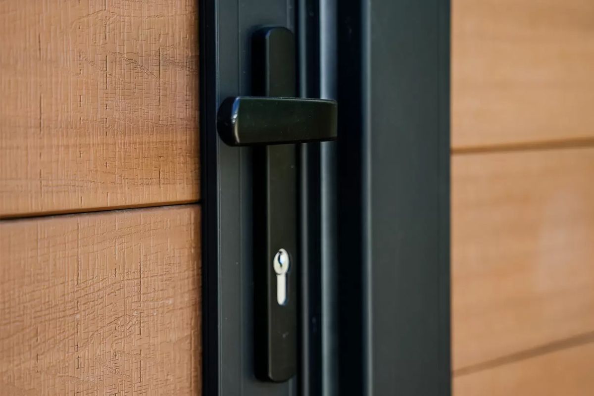 Black door handle with keyhole on a wooden door.