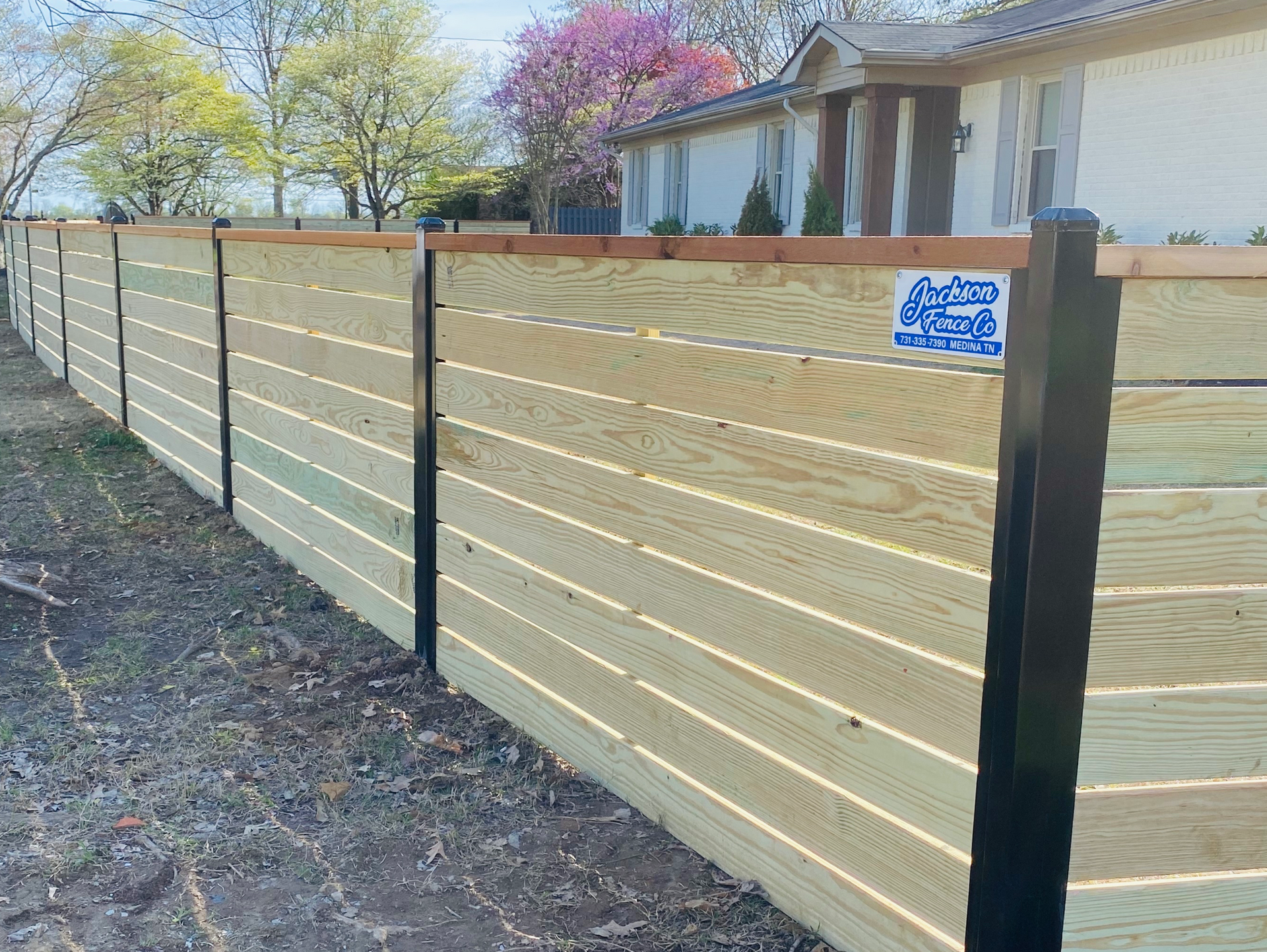 A wooden fence is surrounding a house in a residential area.