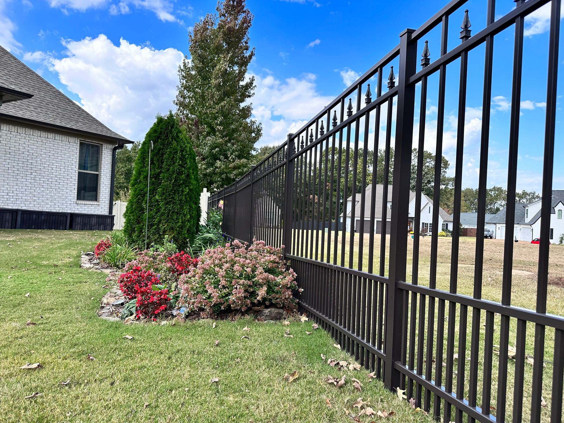 A close up of a black fence with a blue sky in the background.