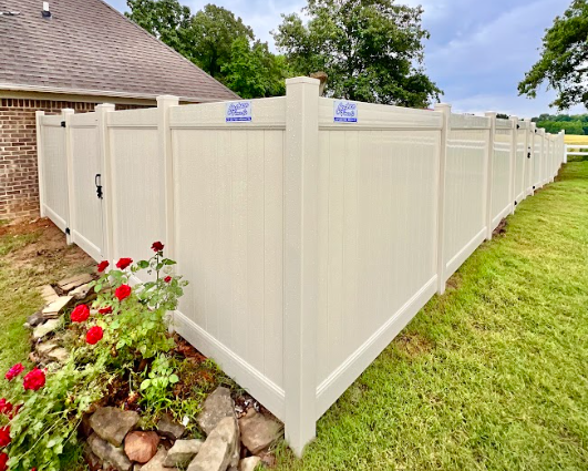 A white vinyl fence with a gate in the backyard of a house.