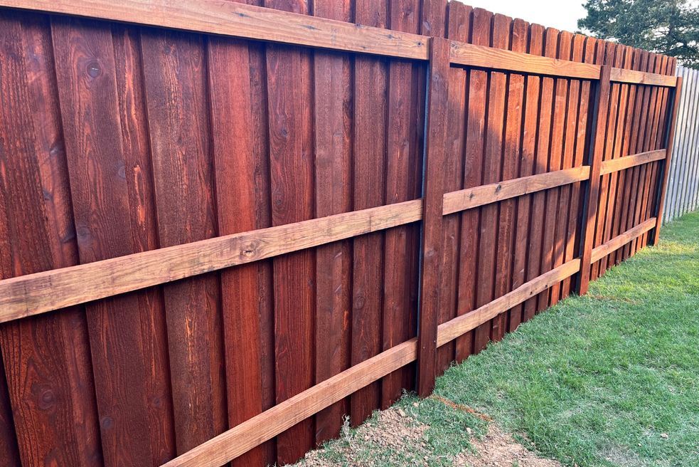 A wooden fence is sitting in the middle of a lush green field.