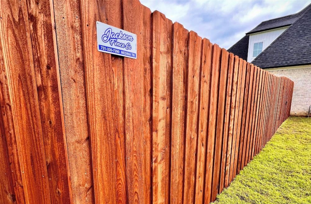 A wooden fence with a sign on it in front of a house.