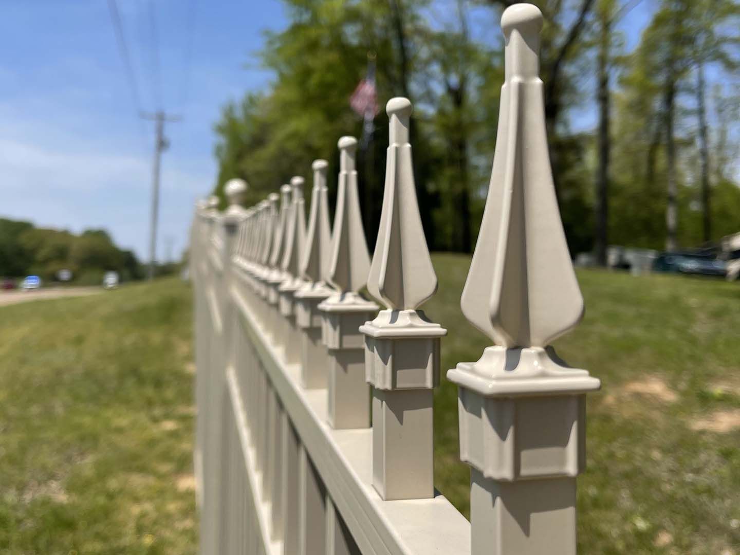 A close up of a white fence with a flag in the background.