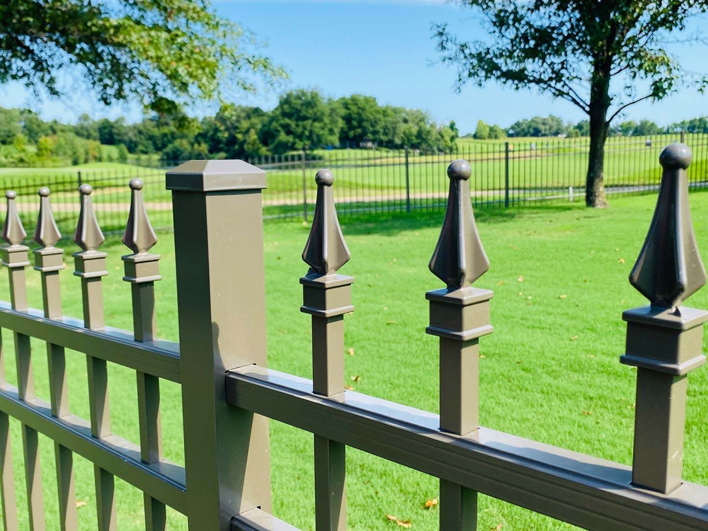 A fence surrounds a lush green field with trees in the background