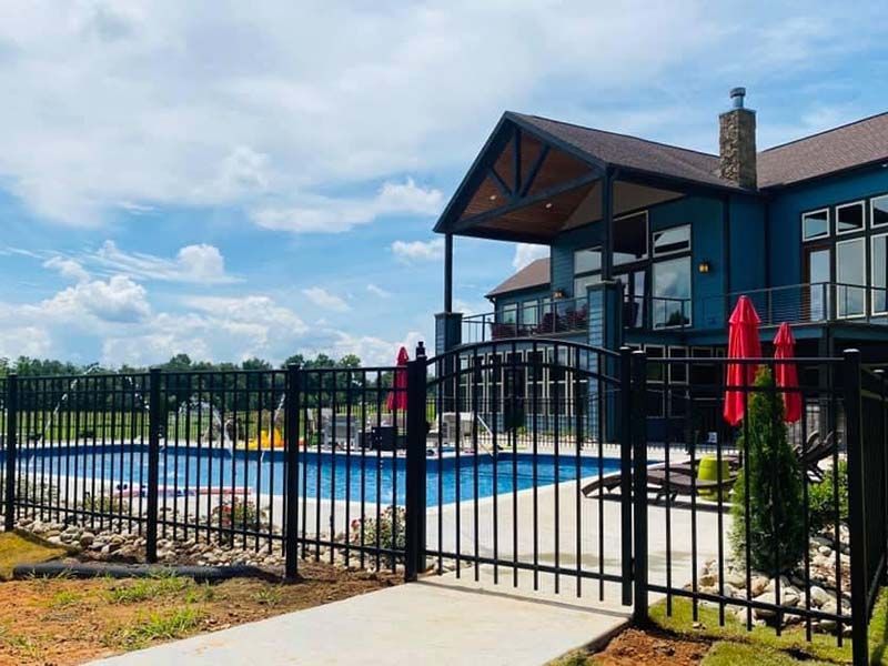A large house with a swimming pool behind a fence.