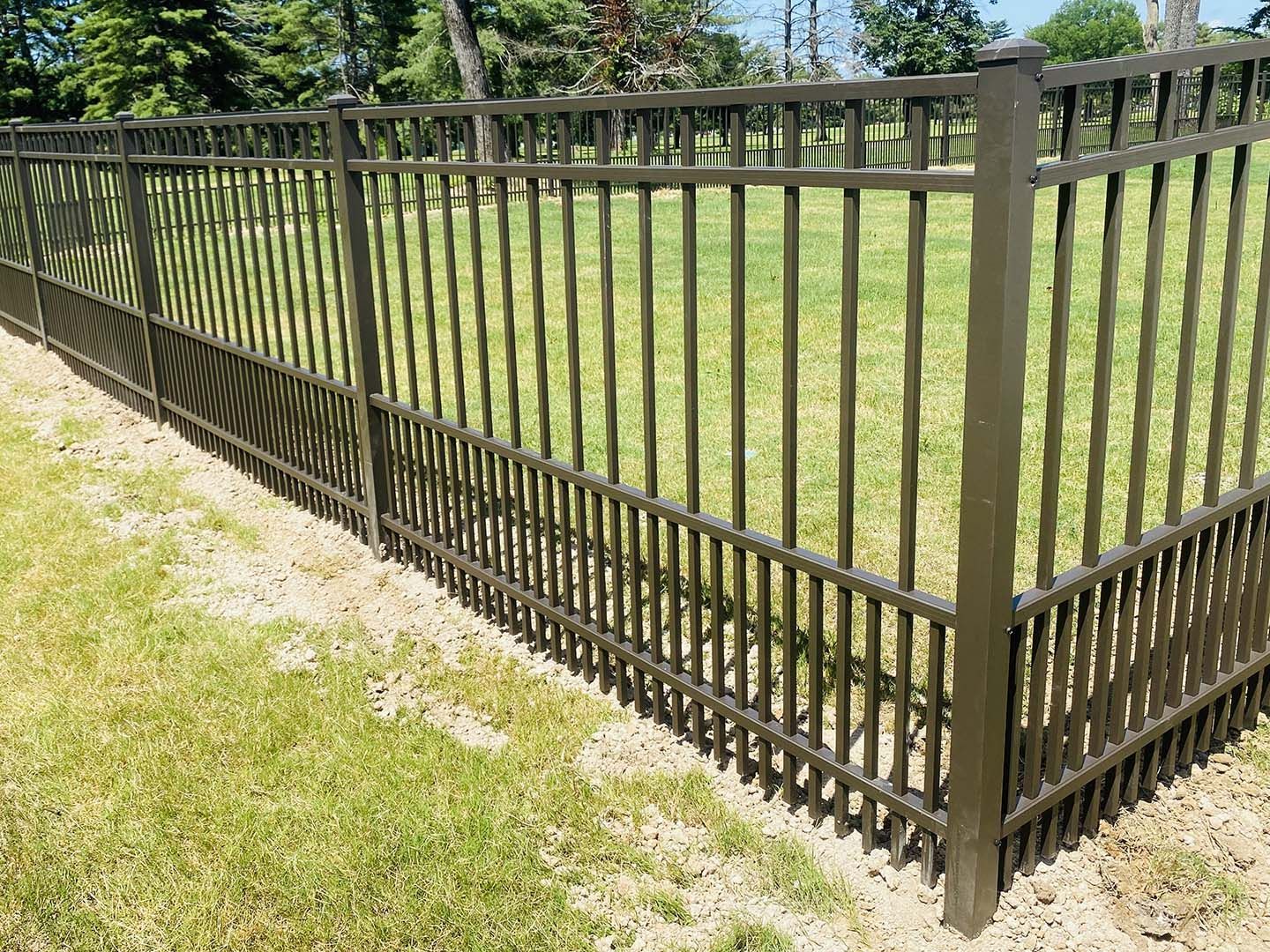 A metal fence surrounds a lush green field.