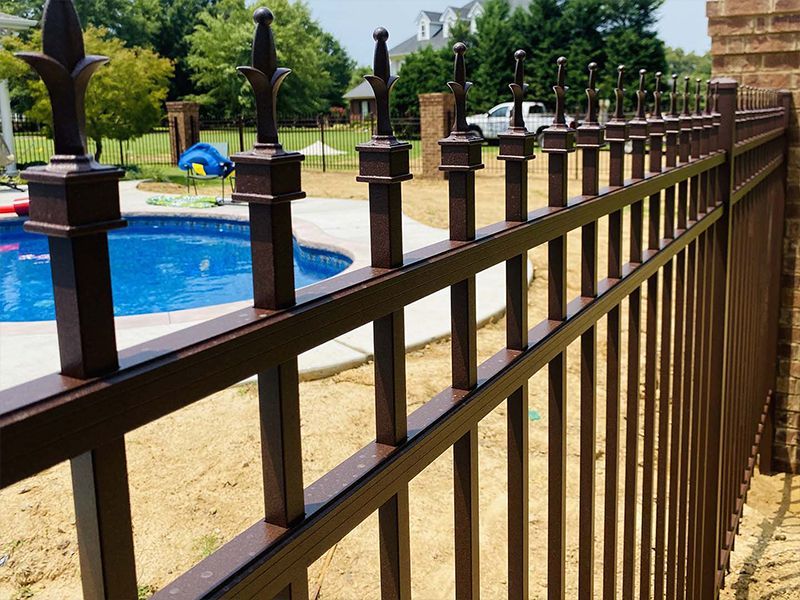 A metal fence surrounds a pool in a backyard