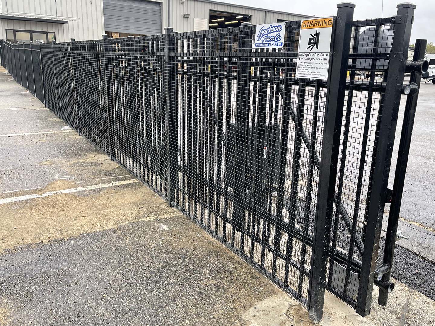 A black metal fence is surrounding a parking lot.