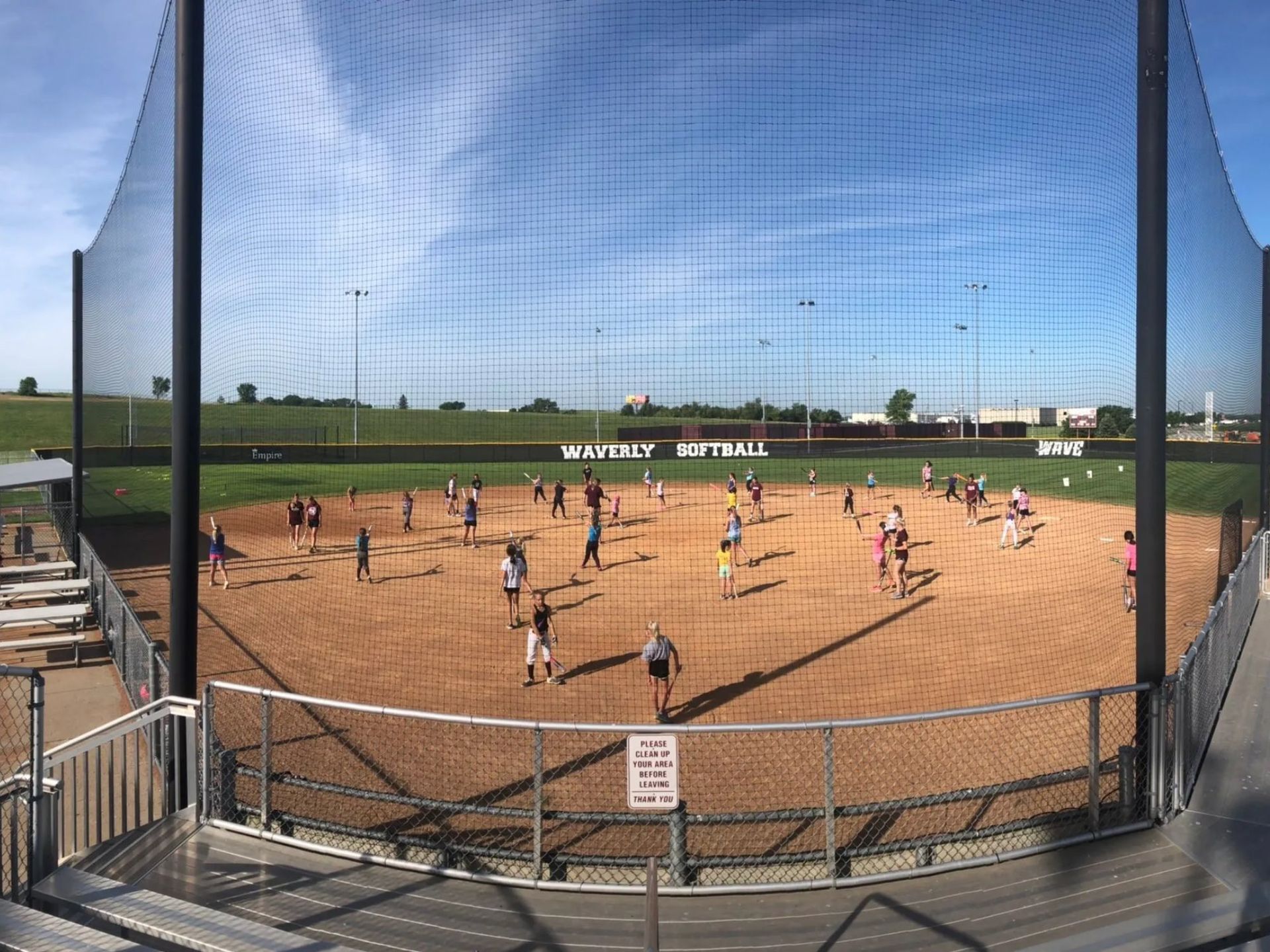 A group of people are playing baseball on a field behind a fence.