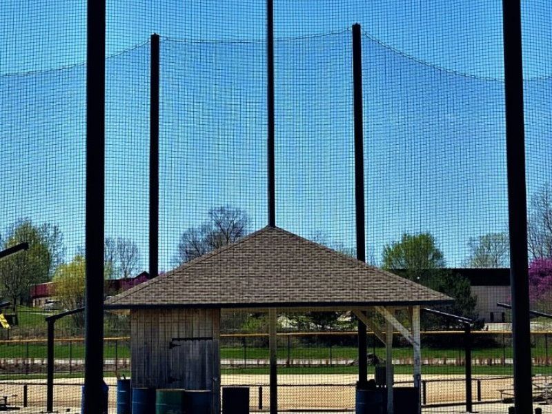 A baseball field with a fence and a shelter behind it.