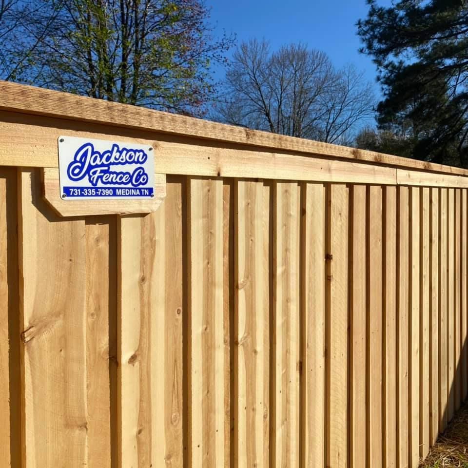 Wooden fence with company sign, against a sunny blue sky.