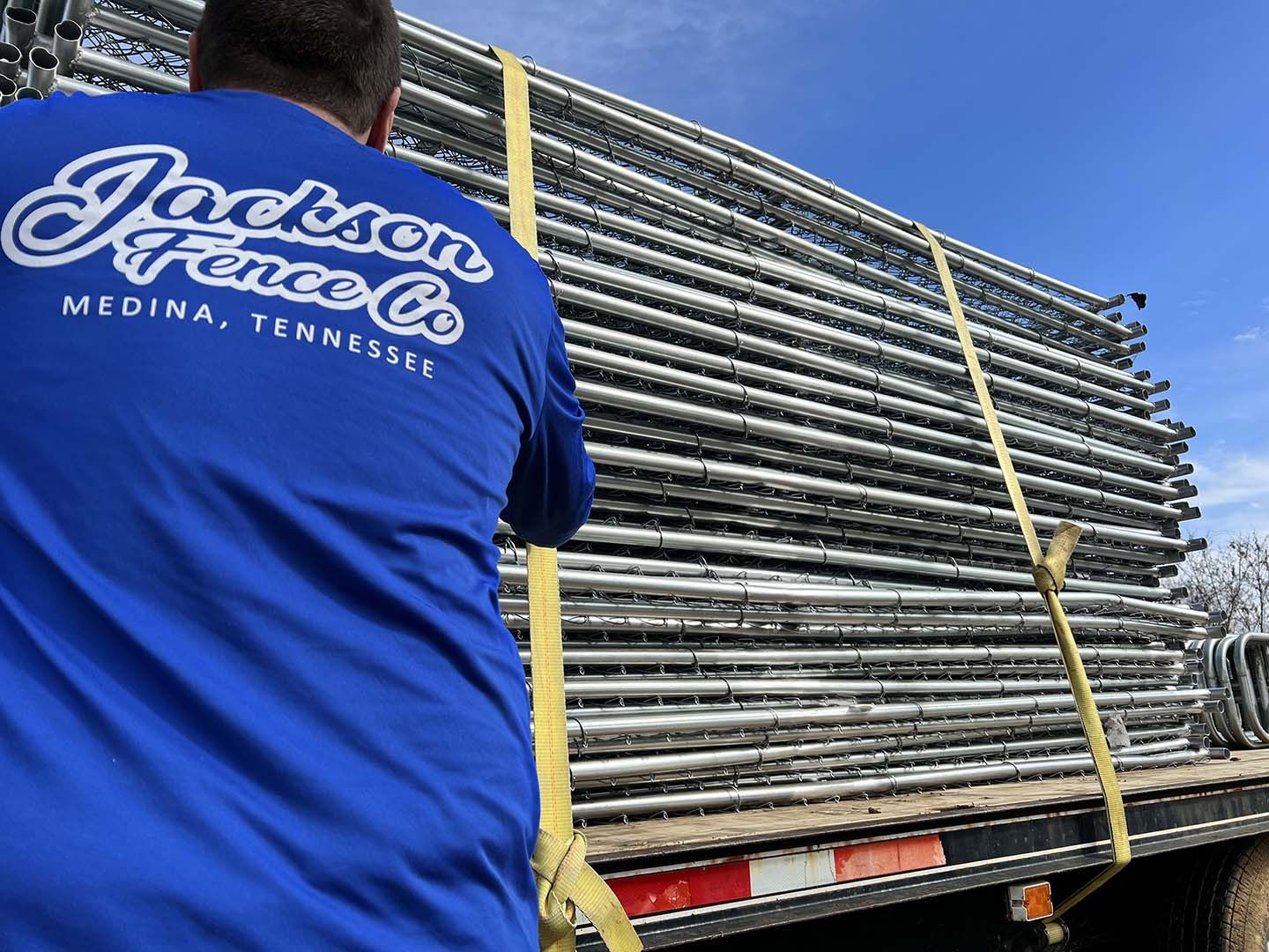 A man wearing a blue shirt that says jackson fence co.