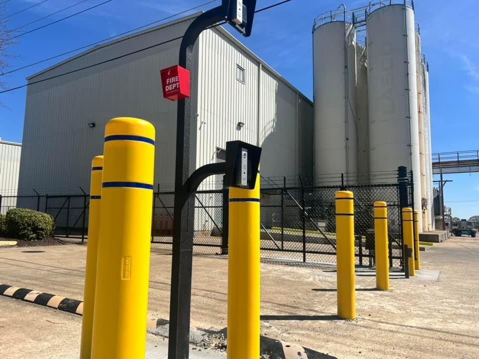 A wooden fence in a parking lot with a dumpster in the background