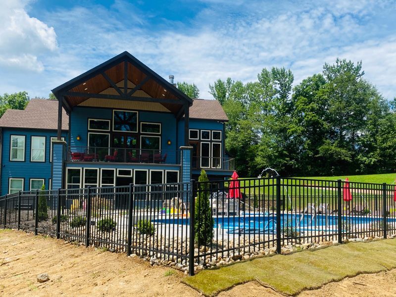 A large blue house with a fence around it and a pool.