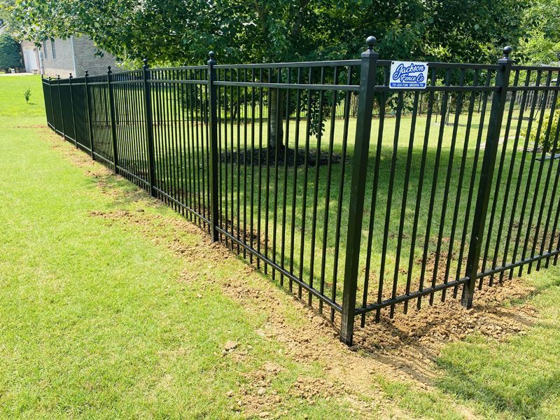 A black metal fence surrounds a lush green yard.