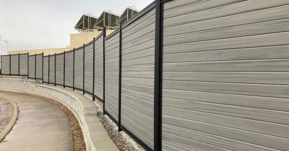 Gray composite fence with black metal frame curving along a walkway.