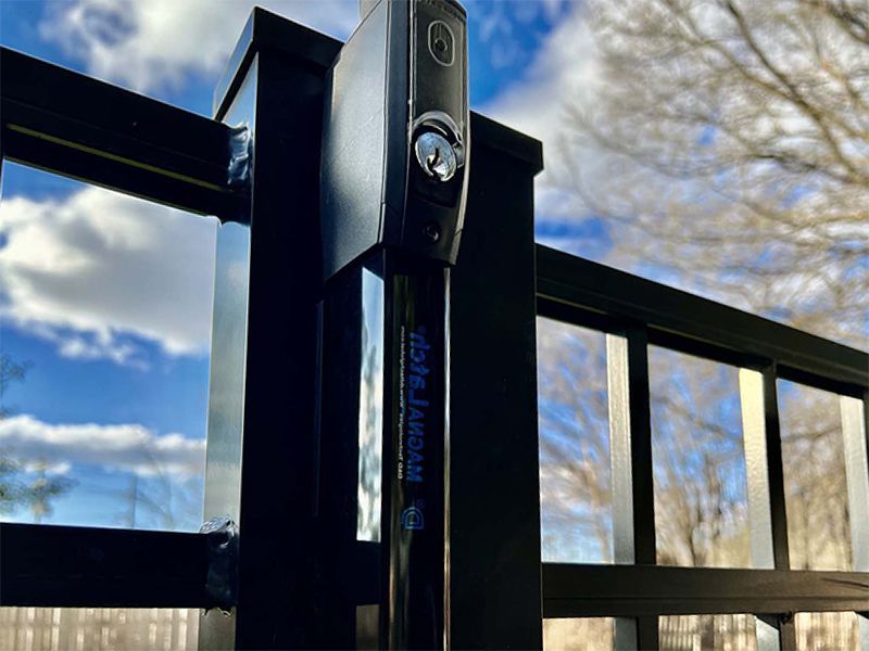 A close up of a black metal fence with a blue sky in the background.