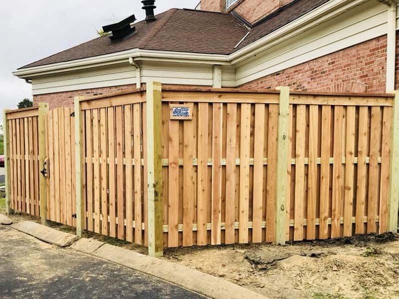 A wooden fence is sitting in front of a brick house.