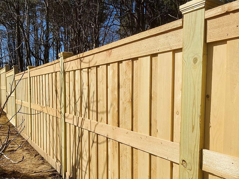 A wooden fence is surrounded by trees on a sunny day.